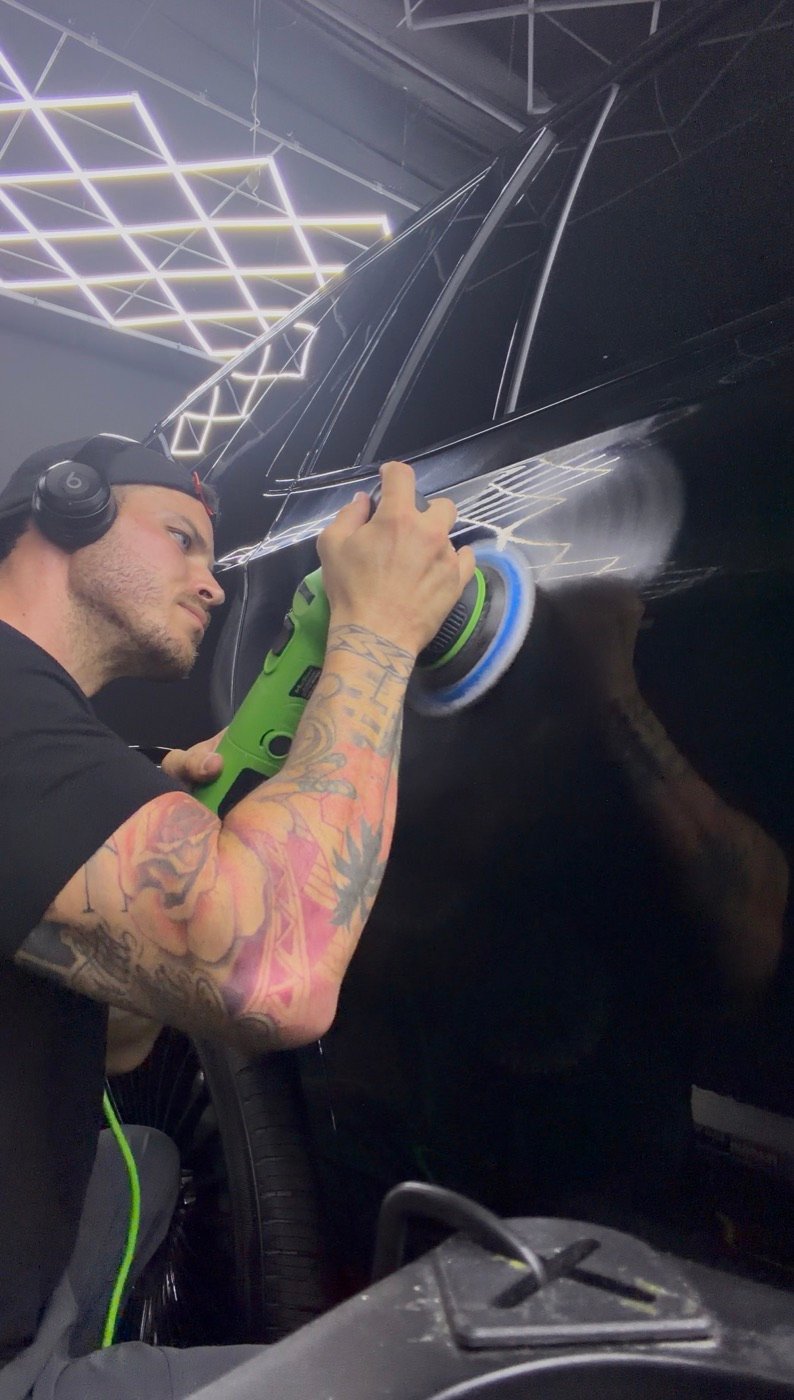 Close-up of machine polishing on a black vehicle door