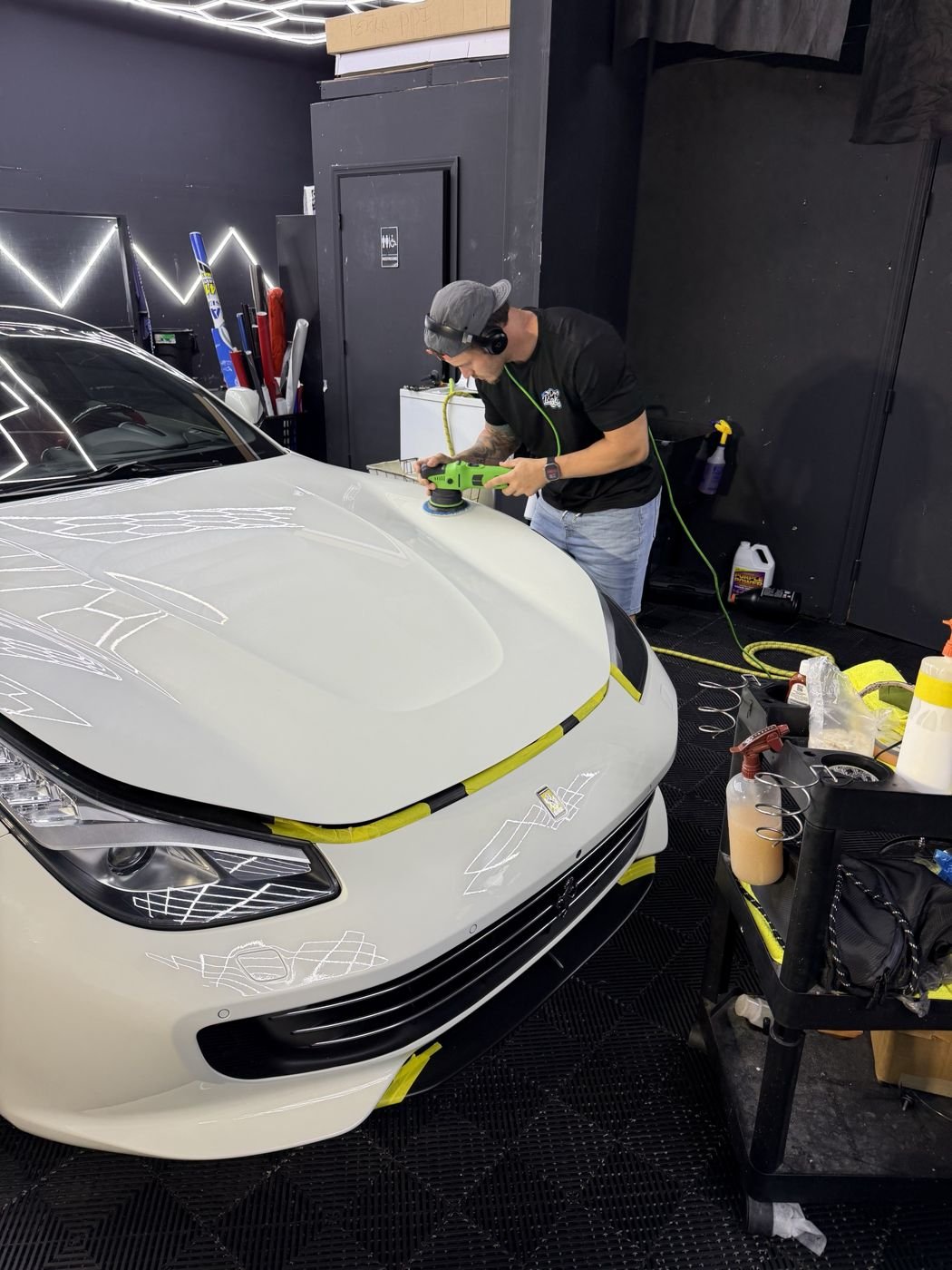 Adham polishing the hood of a white Ferrari in the Minty shop